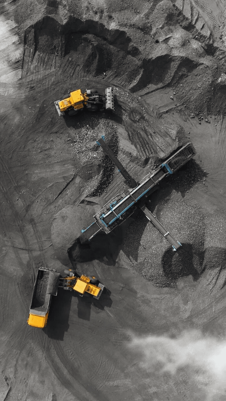 Area stockpile tambang dengan loader, conveyor, dan dump truck dari udara